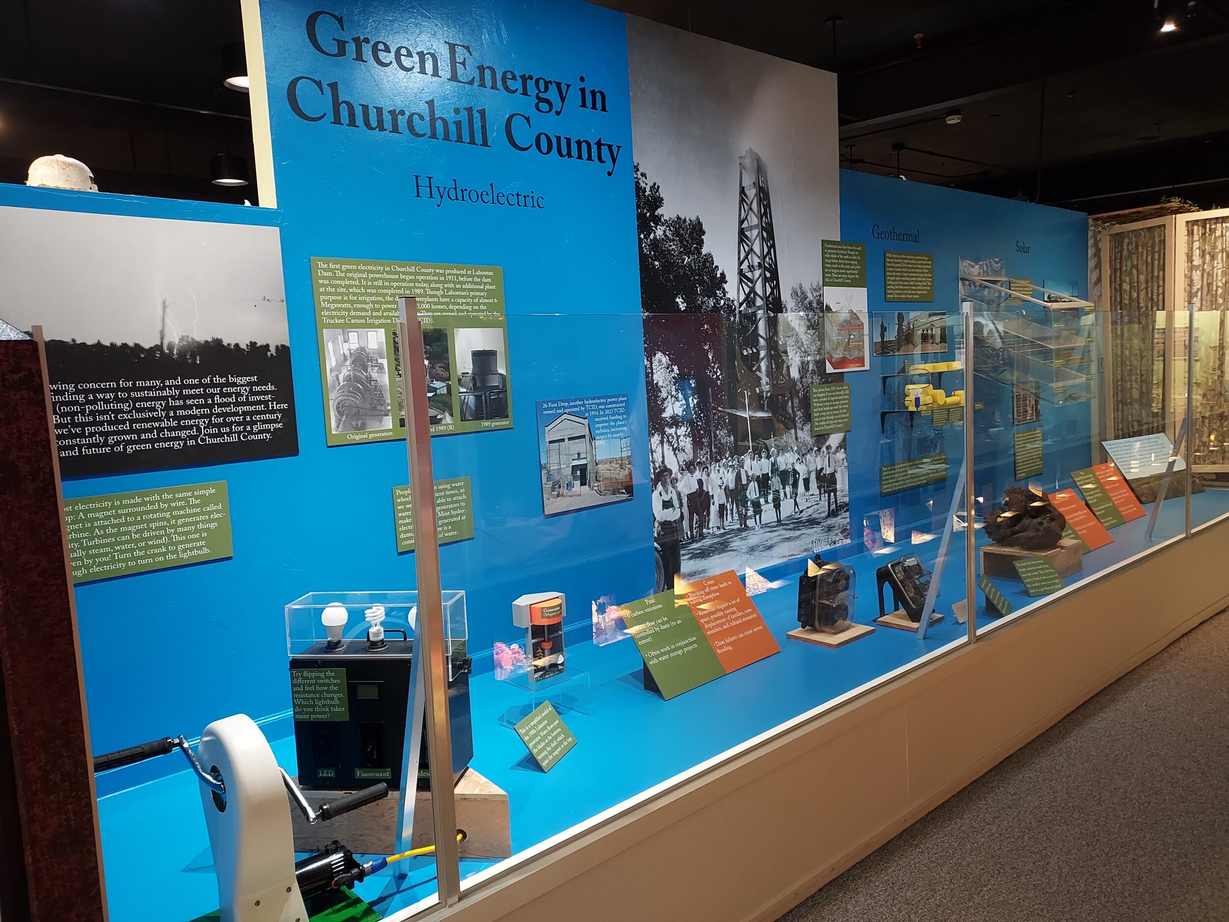 A photograph of the museum exhibit, featuring objects, panels, photographs, and a massive image of steam erupting from an oil derrick
